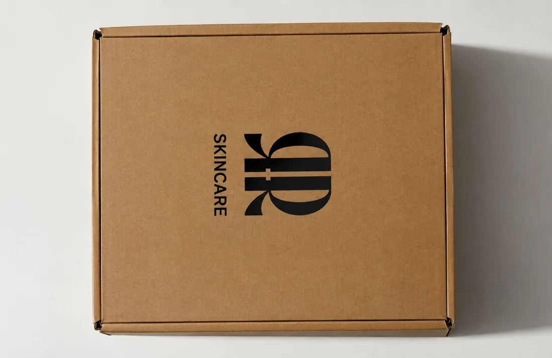 A kraft mailer box printed with a skincare brand mark.
